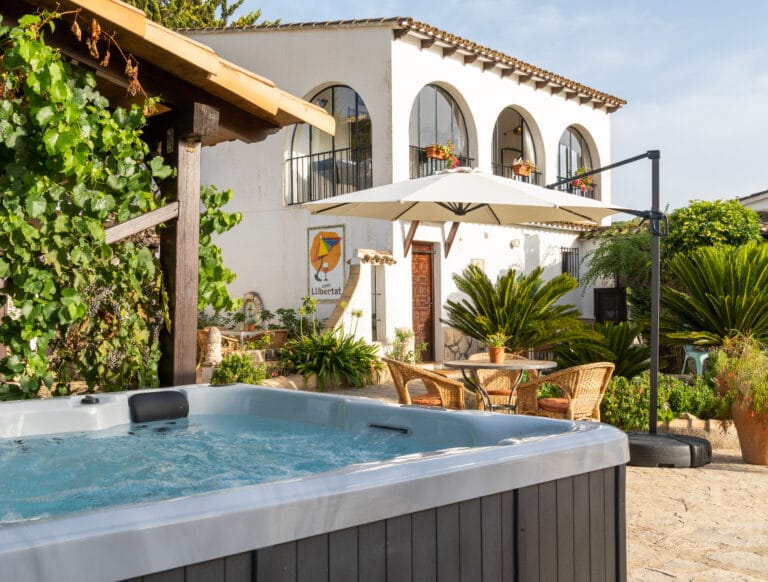 Zonnig buitenterras met comfortabele zitstoelen en parasol bij Casa Libertat.