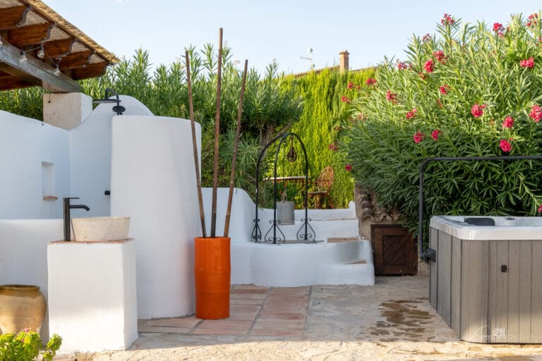 Rustiek buitengedeelte met traditionele wasbak en omliggend groen bij Casa Libertat.